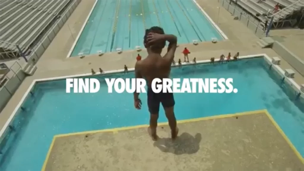 A young, dark-skinned boy on the edge of a 10m high diving board, looking at the pool below him. A text overlay says "Find Your Greatness".