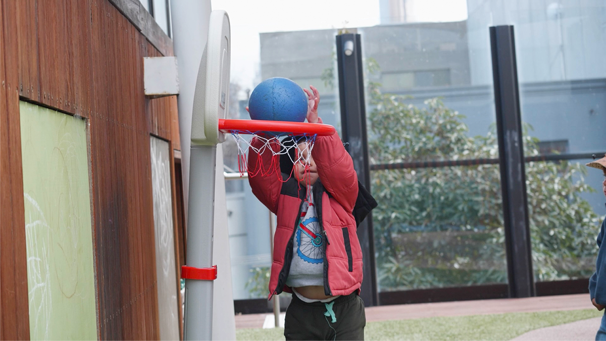 A pupil of Evoke Early Learning attempts to throw a basketball.