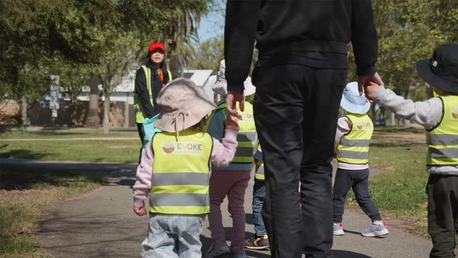 Toddler holding the hand of an Evoke Early Learning staff member.