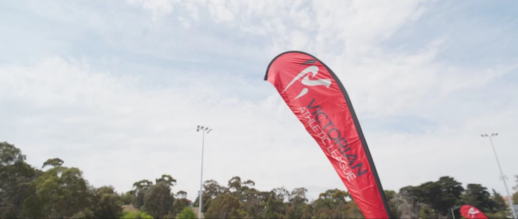 A red Victorian Athletic League flag waving in the wind at The 2023 Essendon Gift