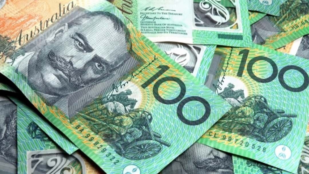 A pile of Australian $100 bills spread over a table on top of each other.