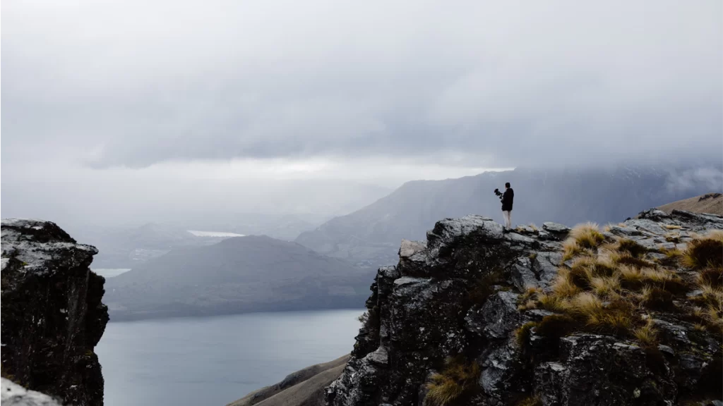 Fixon Media Group Director, Didier Le Miere, standing on the edge of a rocky mountain in Queenstown, New Zealand, overlooking the township.