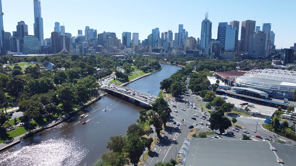 A drone shot of Melbourne's skyline on a summer's afternoon. The Yarra river can be seen in the bottom left of frame, turning into the middle of frame.