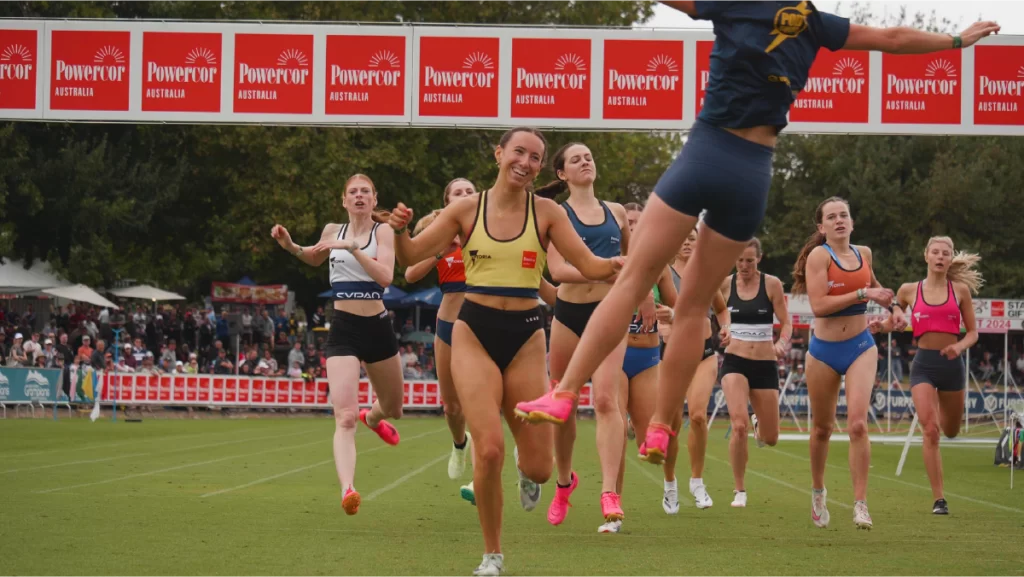 Halle Martin wins the Women's 400m final at the 2024 Stawell Gift and is embraced by teammates as she crosses the finish line.