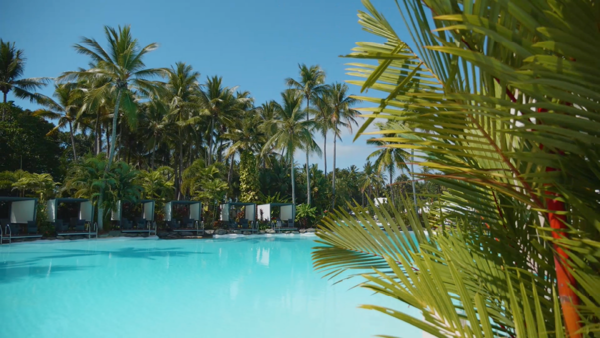 The Sheraton Grand Mirage Resort in Port Douglas. In image, a blue lagoon pool with palm trees and bathing boxes.