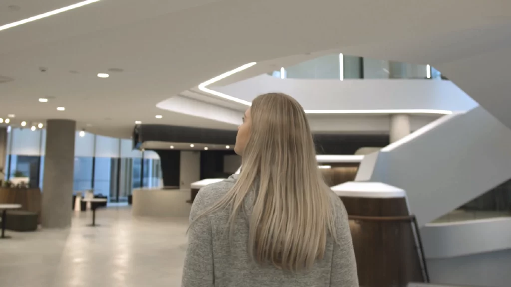 A blonde haired female student walks through a Deakin Business School common area.